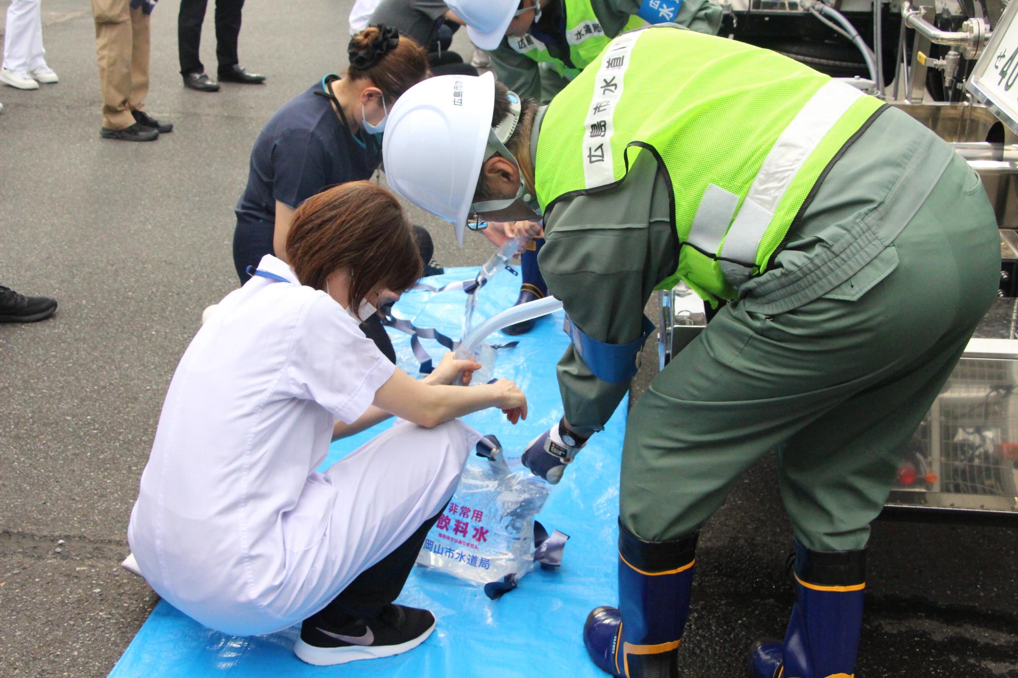 給水車から水を持ち運びできる給水袋に入れる作業の写真